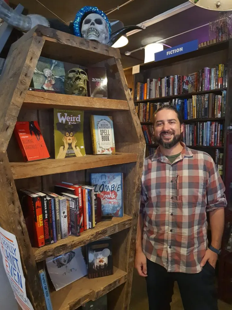 A man standing in front of shelves with books.