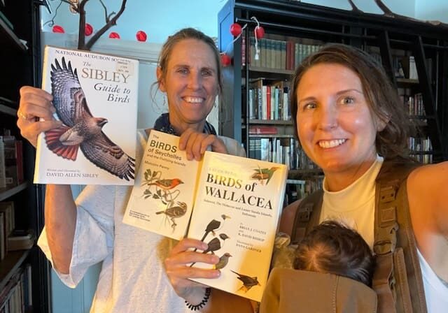 Two people holding bird guide books